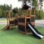 Casetta gioco in legno con scivolo per bambini nel parco giochi.