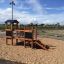 Fortress Nature playhouse with slide in un parco giochi sabbioso