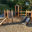 Fortress Nature playhouse with slide in un ambiente da parco giochi