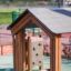 Fortress Nature playhouse with slide e parete da arrampicata in un contesto di parco giochi