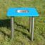 Sand & Water Table su erba verde con superficie blu e gambe in metallo.