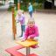 Ragazza seduta su Square bench and table nel parco giochi.