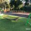 Altalena verde per bambini installata su erba artificiale.