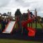 Castello Mastodon con scivolo in un parco giochi con bambini che giocano