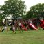 Bambini che giocano sul parco giochi del castello Mastodon con scivolo.
