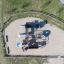 Castello Mastodon con scivolo in un parco giochi sabbioso recintato.