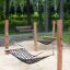 Due Hammock altalene a rete montate su pali di legno in un'area giochi sabbiosa in un parco.