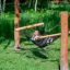 Bambino che si rilassa in un'amaca di rete nera tra pali di legno in un parco verde
