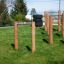 Struttura da arrampicata per parco giochi all'aperto Single Somersault Nature con pali di legno e barre metalliche.