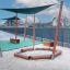 Sun Shade Triangle 3x3x3 Pioneer (Larchwood) installato sopra la sabbiera del parco giochi con pali di legno