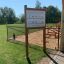 Pannello informativo esterno in un parco giochi con vegetazione circostante