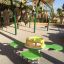 Attrezzatura da gioco verde e gialla Clover rocking in un parco giochi soleggiato