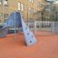 Aztec arch steel structure su una superficie arancione di un parco giochi in un contesto scolastico urbano.