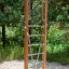 Vertical wooden ladder in un parco giochi circondato da alberi.