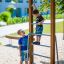 Bambini che giocano su una scala verticale in legno in un'area giochi.