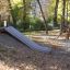 Hill Slide h150 in un parco giochi circondato da alberi in autunno.