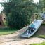 Bambino che scivola giù da Hill Slide Wide h150 in un parco giochi.