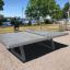 Concrete table tennis, free-standing su un patio all'aperto vicino all'acqua.
