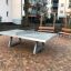 Concrete table tennis, free-standing su un cortile pavimentato con panchine sullo sfondo
