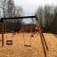Swing Frame (double swing) in un parco giochi con trucioli di legno e uno scivolo sullo sfondo