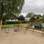 Swing Frame (double swing) in un parco giochi con uno scivolo e strutture per arrampicarsi.
