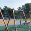 Swing Frame (double swing) in un parco giochi colorato con altre strutture da gioco sullo sfondo