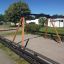 Swing Frame (double swing) in un parco giochi con travi di supporto in legno e superficie sabbiosa.