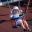 Bambino che si diverte su Swing Frame (double swing) in un parco giochi