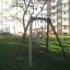 Swing Frame (single swing) in un'area giochi con edifici residenziali sullo sfondo.