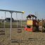 Struttura metallica per doppia altalena e struttura da parco giochi in un parco giochi sabbioso.