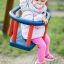 Bambino seduto in un Swing seat: Baby seat blu e rosso.