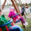 Bambini che giocano su un seggiolino a dondolo: seggiolino per bebè in un parco giochi.
