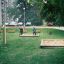 Swing seat: Flexi seat in un parco verde con sabbiere e bambini che giocano