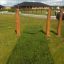 Swing seat: Flexi seat installato all'aperto in un'area erbosa con pilastri di legno.