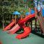 Slide rosso in un parco giochi con alberi sullo sfondo