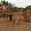 Panther wooden playhouse in un parco giochi sabbioso con strutture da arrampicata e scivoli.