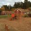 Panther wooden playhouse in un parco giochi con scivoli e strutture per arrampicarsi.