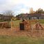 Panther wooden playhouse in un parco giochi sabbioso con altalena e parete da arrampicata.