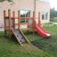 Struttura in legno Mini play con scivolo rosso e rampa da arrampicata in un parco giochi in giardino