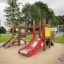 Struttura da parco giochi per bambini con uno scivolo rosso ed elementi in legno Mini play
