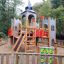 Parco giochi in legno Camelot Castle con scivolo ed elementi di arrampicata per bambini.