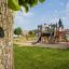 Parco giochi Camelot castle with slide in un parco verde.