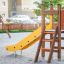 Pi scivolo giallo per parco giochi con gradini in legno in un'area sabbiosa