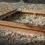Sandpit in legno riempito di sabbia in un parco giochi circondato da foglie autunnali.