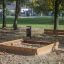Sandpit in legno all'aperto in un parco con una panchina nelle vicinanze