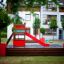 Grocer's single slide in un moderno parco giochi con elementi rossi e in legno.