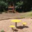 Tavolo e sedie da parco giochi gialli Daisy in un'area sabbiosa.
