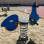 Attrezzatura da gioco Scooter rocking con design blu e giallo in area sabbiosa