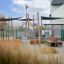 Sun Shade Triangle 3x3x3 Nature (Robinia) che fornisce ombra in un'area giochi con panchine e verd