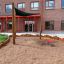 Sun Shade Triangle 3x3x3 Nature (Robinia) installato nel parco giochi accanto a un edificio in mattoni rossi.